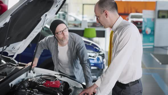 Sales Manager and Client Near a New Car with an Open Hood