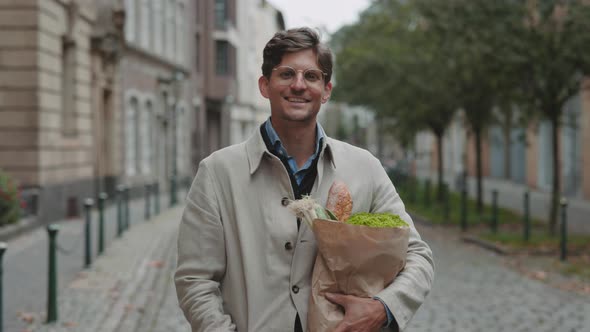 Man Smiling on Camera While Standing with Grocery Bag