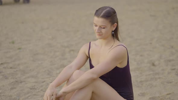 Attractive girl sitting in the sand brushing her hands