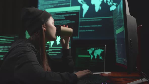 Asian Woman Hacker Using Computer Hacking And Drinking Coffee, Code On Multiple Computer Screens