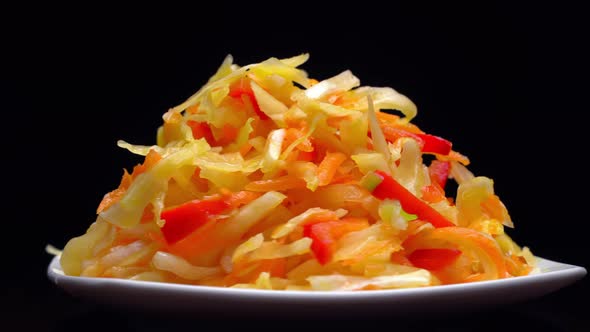 salad of fresh vegetables on a white plate rotates on black background.