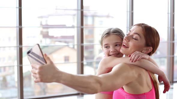 A fitness woman with her daughter uses a smartphone for training
