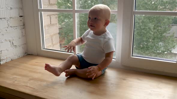 Child Sits on a Wide Windowsill