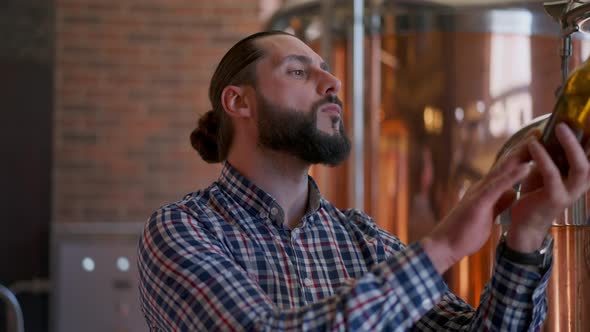 Expert Male Brewer Looking at Beer Bottle Thinking