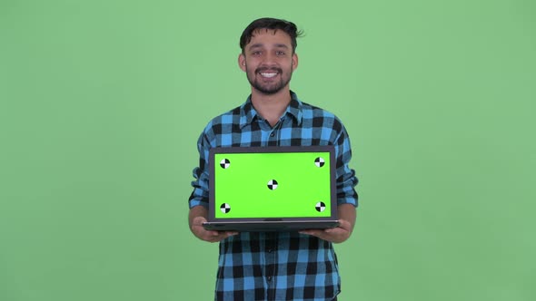 Happy Young Bearded Persian Hipster Man Talking While Showing Laptop