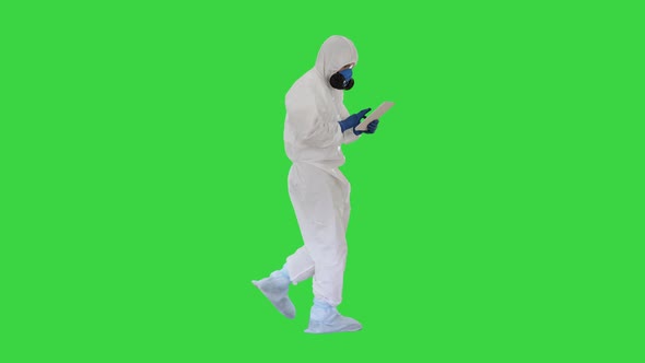 Scientist or Docrot Wearing Biohazard Suits and Protective Masks Using Digital Tablet While Walking