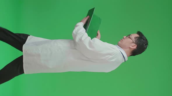 Asian Doctor With Stethoscope Reading Document While Walking On Green Screen