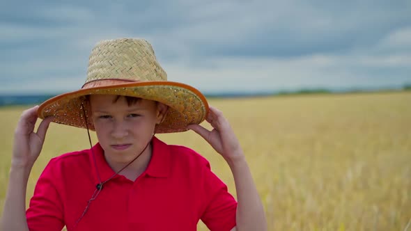 Boy in straw hat standing in wheat field