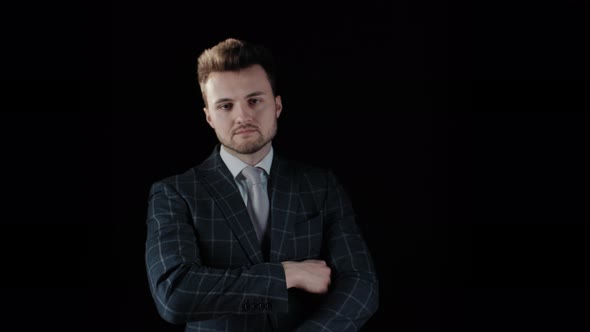 Handsome Confident Businessman Wearing Suit with Arms Crossed Isolated on Black Background