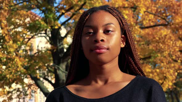 Young Beautiful Black Woman Smiles To Camera in the Park in Autumn Day