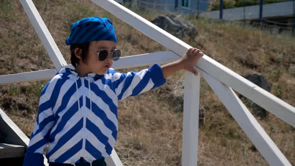 Boy Child in a Striped Blue Jacket and Bandana Walks