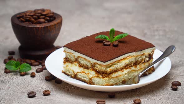 Portion of Traditional Italian Tiramisu dessert and coffee beans on grey concrete background