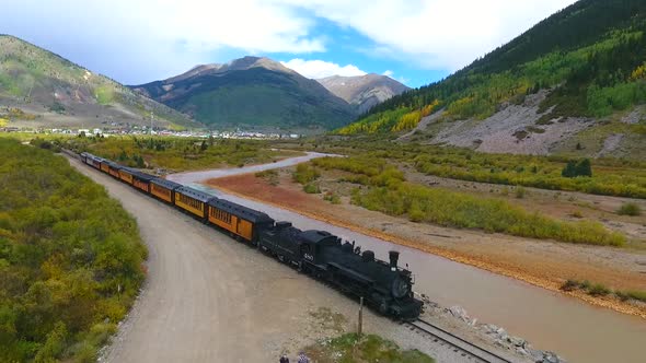 Aerial of Locomotive Train in Mountain Valley By Stream Leaving Silverton for Durango in Colorado