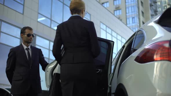 Personal Driver Waiting for Boss on Parking Lot, Helping Her to Get Into Car