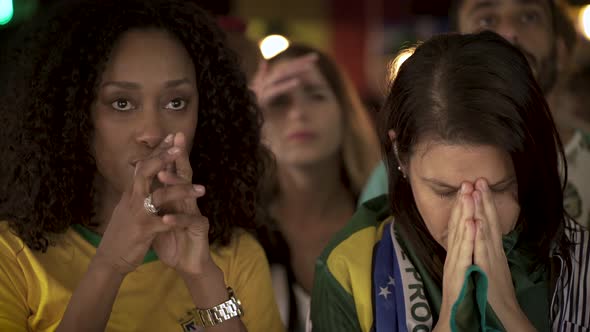 Brazilian football fans looking disappointed while watching televised match in bar