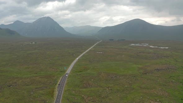 Rising drone shot over winding roads through Scottish highlands