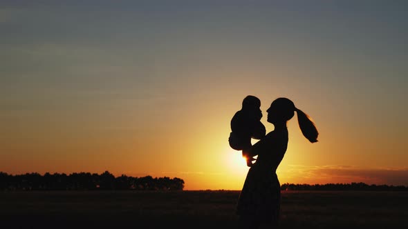 Silhouette of Mother with Baby at Sunset