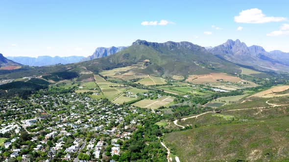 Aerial of suburban neighbourhood and farms in green valley between mountains, Stellenbosch, Coetsenb