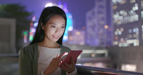 Woman sending message on cellphone in Hong Kong at night