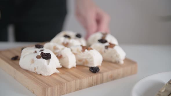 Young woman hands move brown wooden board with tasty pakhlava and dried berries