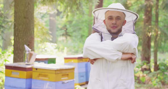 Apiary in the Middle of the Forest Male Young Bearded Handsome Beekeeper in White Protective Suit