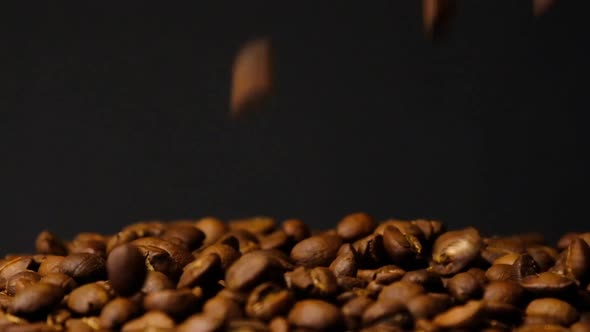 Slow motion of roasted coffee beans falling. Organic coffee seeds.