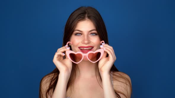 Portrait of a Beautiful Girl in Pink Glasses on a Blue Background