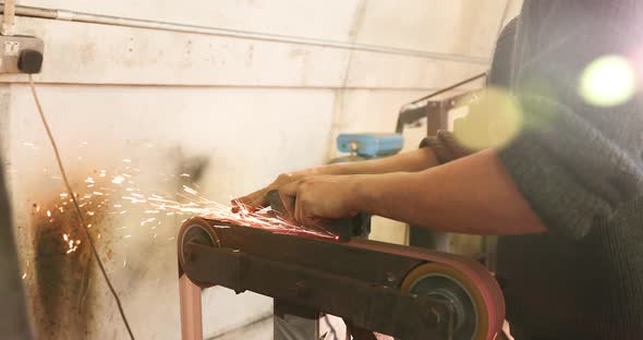 Bladesmith deburring a blade on belt grinder