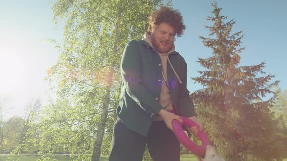 Man Lifting Dog Up in Air while Playing in Park