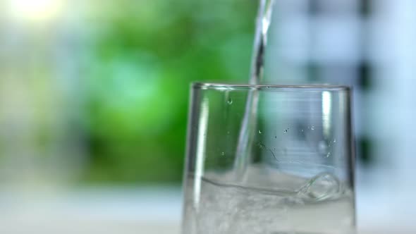 Closeup Pouring Purified Fresh Drink Water From the Bottle on Summer Background