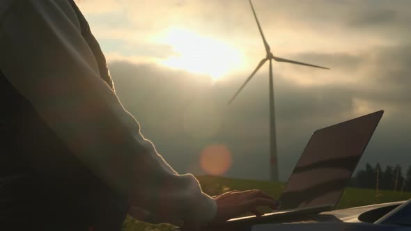 Person Hands Make Notes of Functioning Wind Turbine on Field