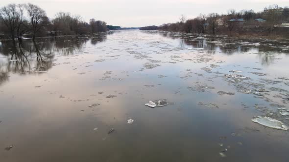 Several Large Dirty White Ice Floes Float Down the Gloomy River