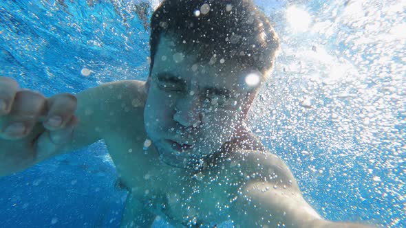 a Man Dives Into the Pool with a Camera in His Hands