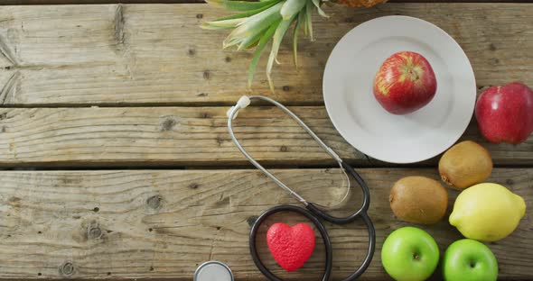 Video of stethoscope, fresh fruit and vegetables with copy space over wooden background