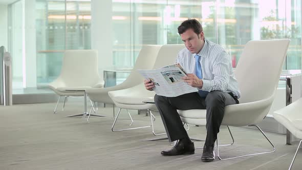 Businessman reading a magazine then looking at the camera