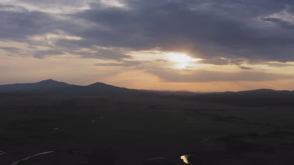 Drone View of a Sunset in a Valley with a River and Mountain Ranges