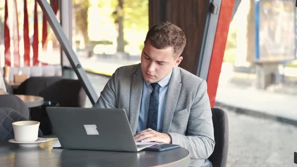 Business Man in Suit Using a Laptop in Cafe