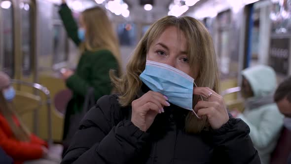 Blonde Woman Putting on Protective Mask in Subway
