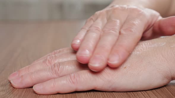 Old Woman Applies White Moisturizing Cream on Wrinkled Hands