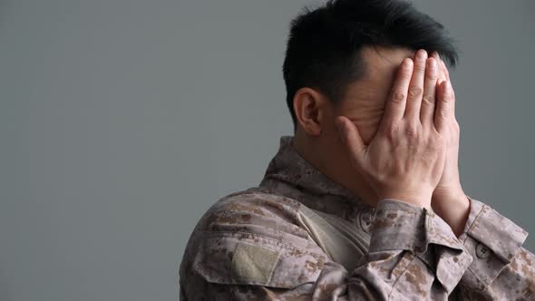 Upset military Asian man covering face with hands
