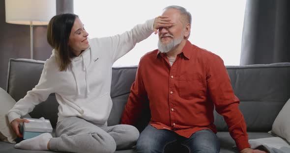 Adult Daughter Granddaughter Taking Red Gift Box to Senior Father Grandfather