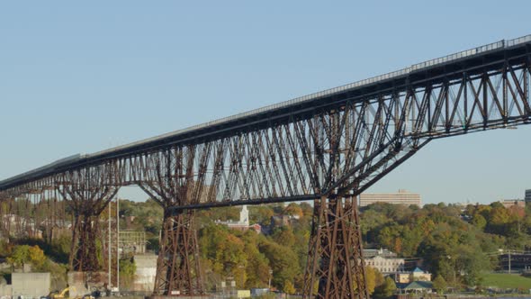 Low angle view of walkway over Hudson river, trees and settlement at distance