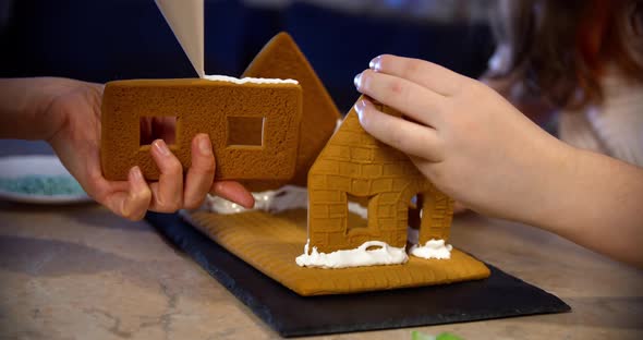Woman and Little Girl Decorate Gingerbread House