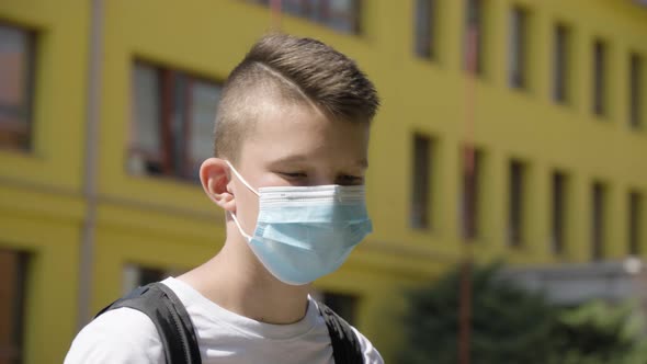 A Caucasian Teenage Boy Takes Off a Face Mask and Looks at the Camera  Closeup  a School