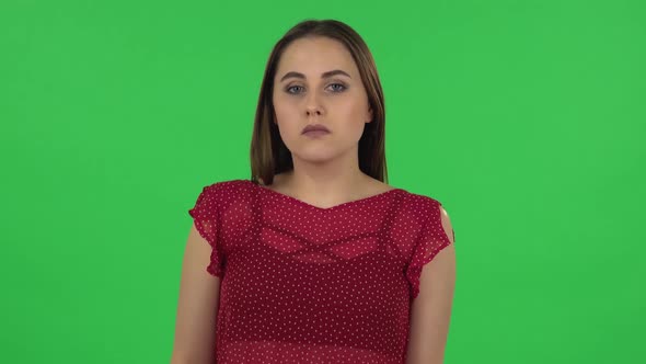 Portrait of Tender Upset Girl in Red Dress Is Shrugging and Sighing. Green Screen