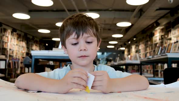 Engaged Young Boy with Brown Hair Examines White Paper Piece