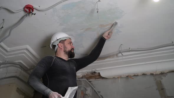 Fat Bearded Adult Man in Protective Helmet and Black Tight Fitting Clothing Remove Construction