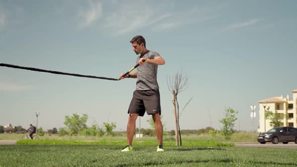 A Man of European Descent Trains with Aerobic Equipment Rubber Bands and Sticks From the Outside