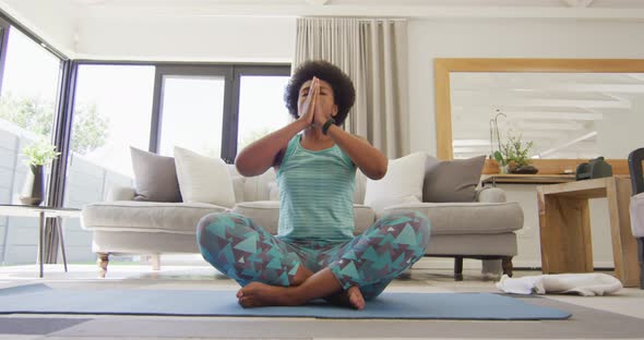 Happy african american wearing sportswear, doing yoga, meditating