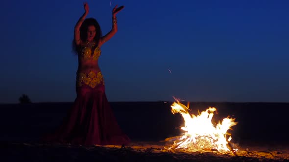 Brunette Dancing Belly Dance Near the Fire, Against a Beautiful Sunset